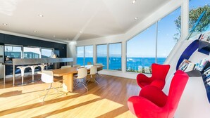 Un intérieur moderne avec un coin repas, de grandes fenêtres et une vue sur l’océan.