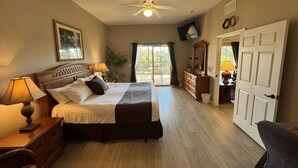 Une chambre avec un grand lit, un ventilateur de plafond, une commode et une porte donnant sur un balcon.