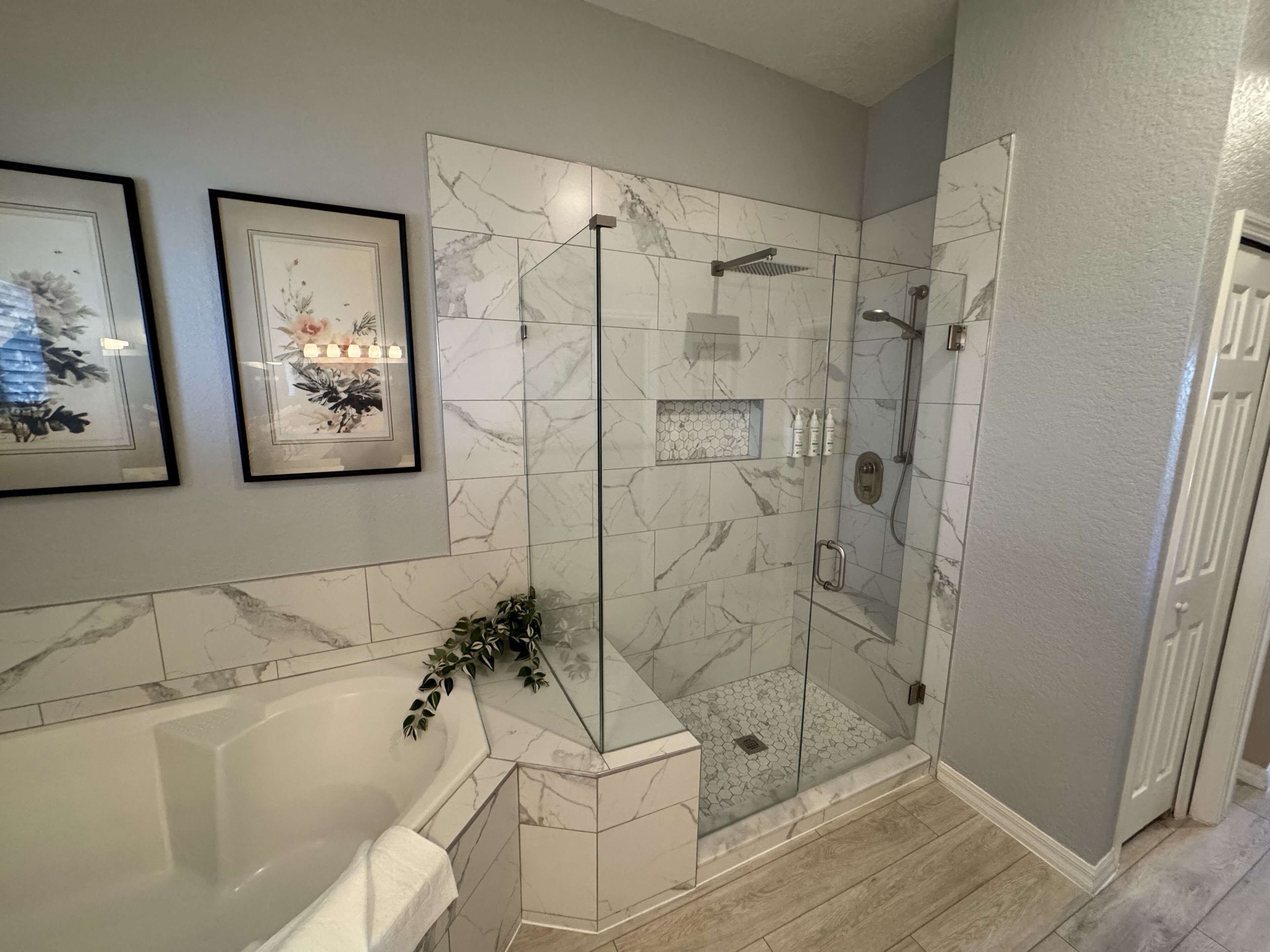 Une salle de bain moderne avec une douche à parois de verre, une baignoire sur pieds et des carreaux de marbre.
