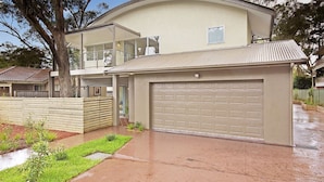 A two-story house with a garage, a balcony, and a tree in the front yard.