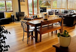 A cozy living room with a wooden dining table, a sofa, and a TV.