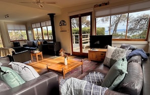 A spacious living room with a large window, a fireplace, a television, and a cozy seating area.