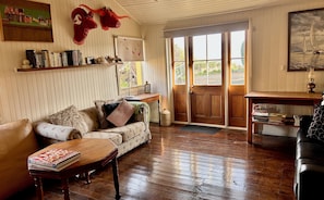 A cozy living room with a wooden floor, a sofa, a coffee table, and a bookshelf.