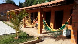 A building with a tiled roof, brick walls, and a paved patio area with a hammock. - Chacara Dois Lagos!   Come and admire nature in this place!   (ITU)