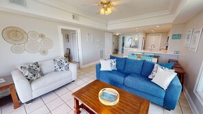 A living room with a white sofa, a blue sofa, and a wooden coffee table.