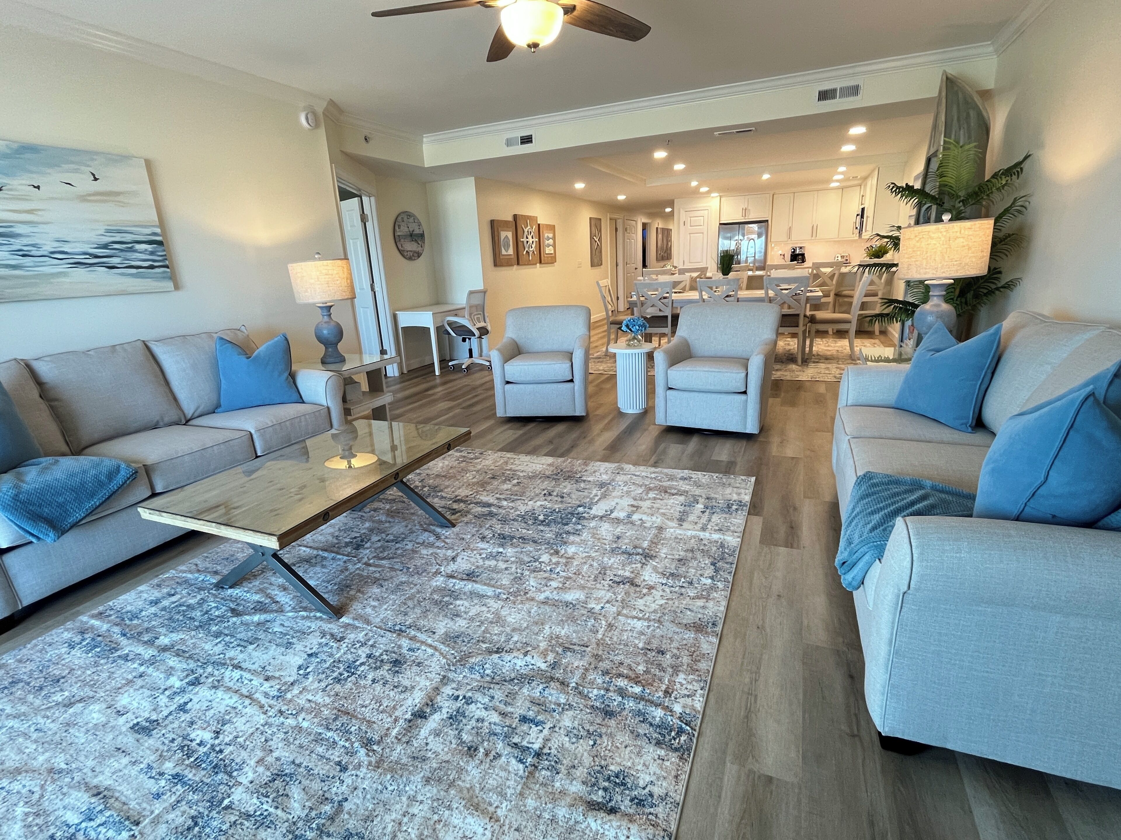 A spacious living room with a large sofa, a coffee table, and a dining area in the background.