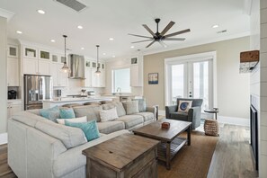A spacious living room with a sectional sofa, a coffee table, and a ceiling fan.