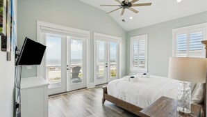 Une chambre à coucher avec un lit, un bureau, une télévision et un ventilateur de plafond.