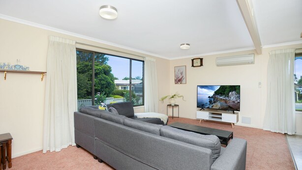 A living room with a grey sofa, a flat-screen TV, and a large window offering a view of the outdoors. - Great Location Stay and Relax (Victor Harbor)