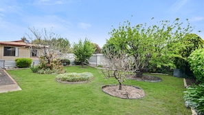 A well-maintained garden with a lawn, flowering plants, and a variety of trees. - Great Location Stay and Relax (Victor Harbor)