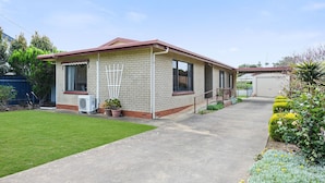 A two-story brick house with a red roof, a front porch, and a paved driveway. - Great Location Stay and Relax (Victor Harbor)