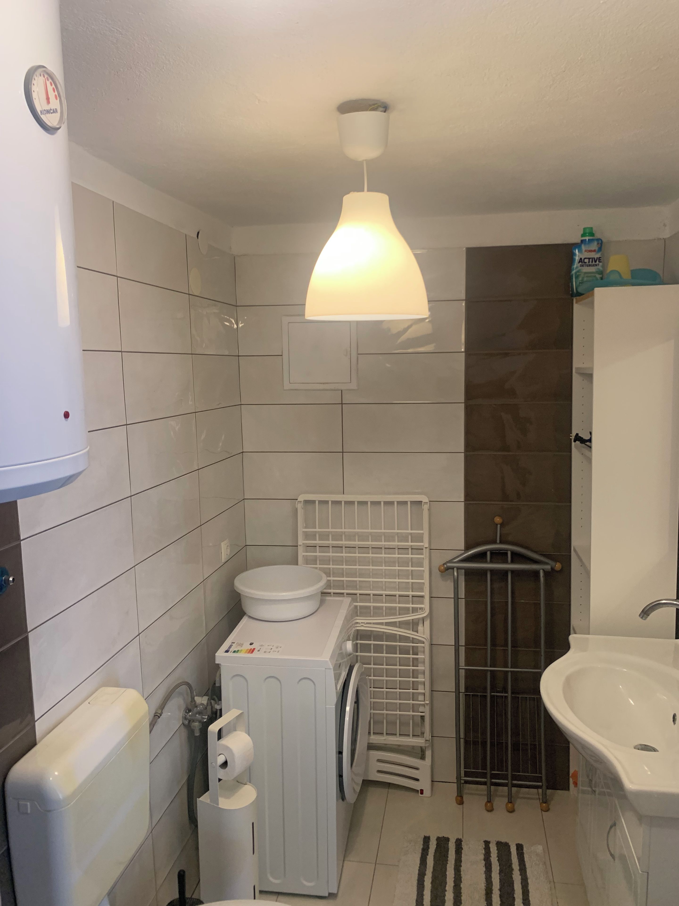 Ein kleines Badezimmer mit Toilette, Waschbecken und einem weißen Heizkörper an der Wand.