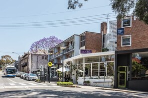 A street view with a cafe, a bus, and a pedestrian crossing sign. - Wake up to Sydney Harbour (Balmain East)