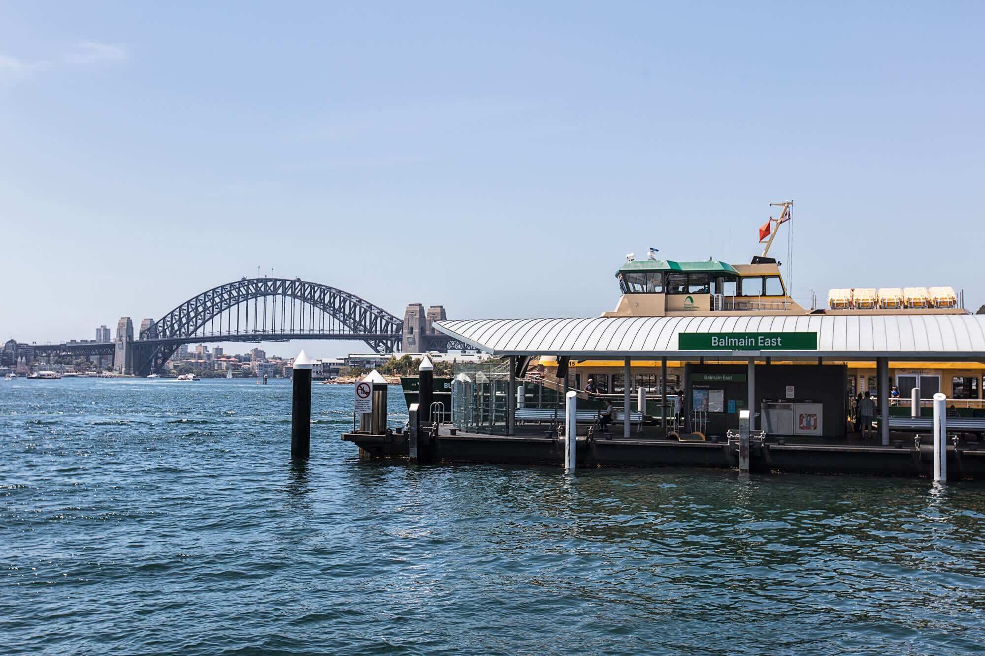 A ferry terminal with a view of the Sydney Harbour Bridge in the background.