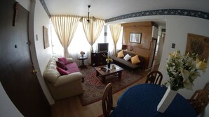 A living room with a sofa, armchairs, a coffee table, and a TV. - QUINTA VERGARA 5 PERSONAS  (Viña)