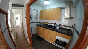 A narrow hallway leading to a kitchen with wooden cabinets, a black countertop, and a stove. - QUINTA VERGARA 5 PERSONAS  (Viña)