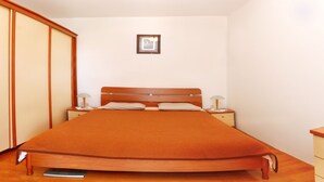 A neatly made bed with a wooden headboard, two bedside tables with lamps, and a framed picture on the wall. - Family-friendly apartment in old fishermen village close to Zadar (Kali)
