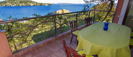 A balcony with a table and chairs, overlooking a body of water and a distant shoreline.