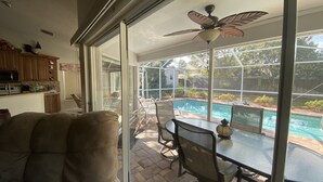 A patio with a glass door leading to a pool area, outdoor furniture, and a ceiling fan. -  3 Bed ~ 2 Bath~  Pool ~ Wifi ~ Pets Welcome ~Optional Heated Pool ~SS Barbecue  (Spring Hill)
