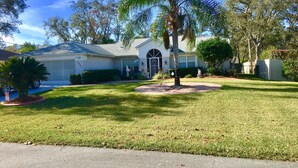 A residential house with a well-maintained lawn, a palm tree, and a driveway. -  3 Bed ~ 2 Bath~  Pool ~ Wifi ~ Pets Welcome ~Optional Heated Pool ~SS Barbecue  (Spring Hill)