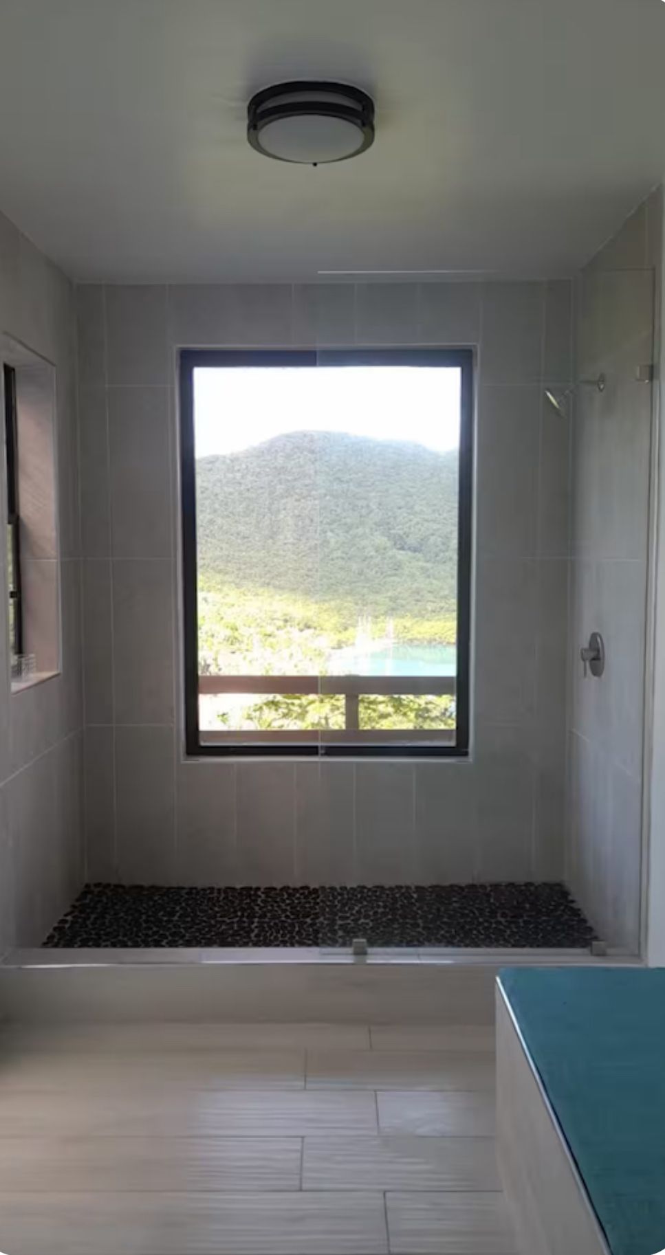Ein Badezimmer mit großem Fenster, einer Badewanne und einer Duschkabine.