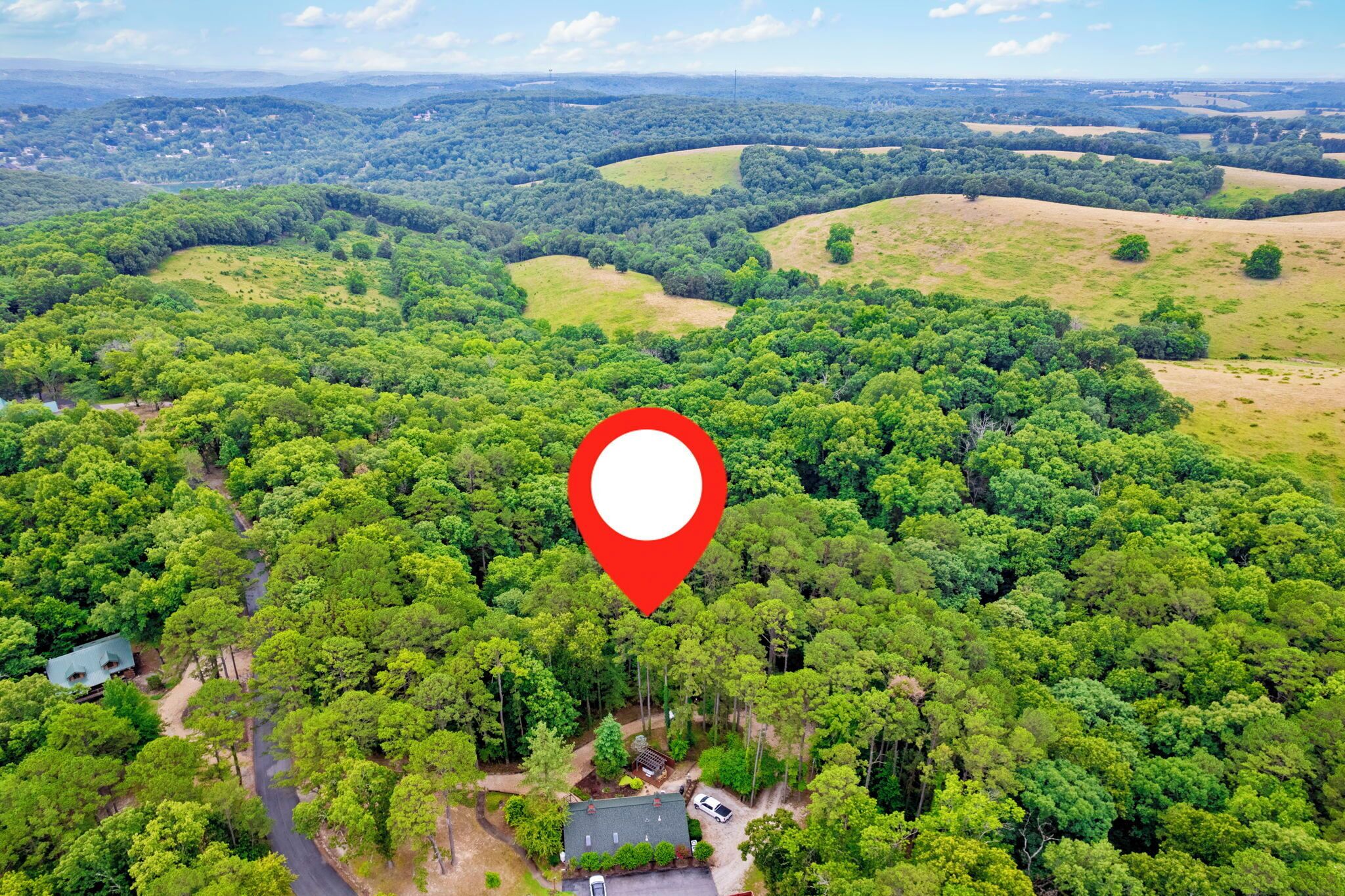 Vue aérienne d’une zone boisée, avec un marqueur rouge indiquant un emplacement précis.