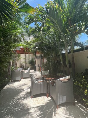 Ein Terrassenbereich im Freien mit Korbmöbeln und Palmen.