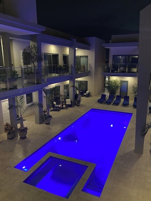 Un espace piscine extérieur moderne, doté d’une piscine rectangulaire, de chaises longues et de plantes en pot.
