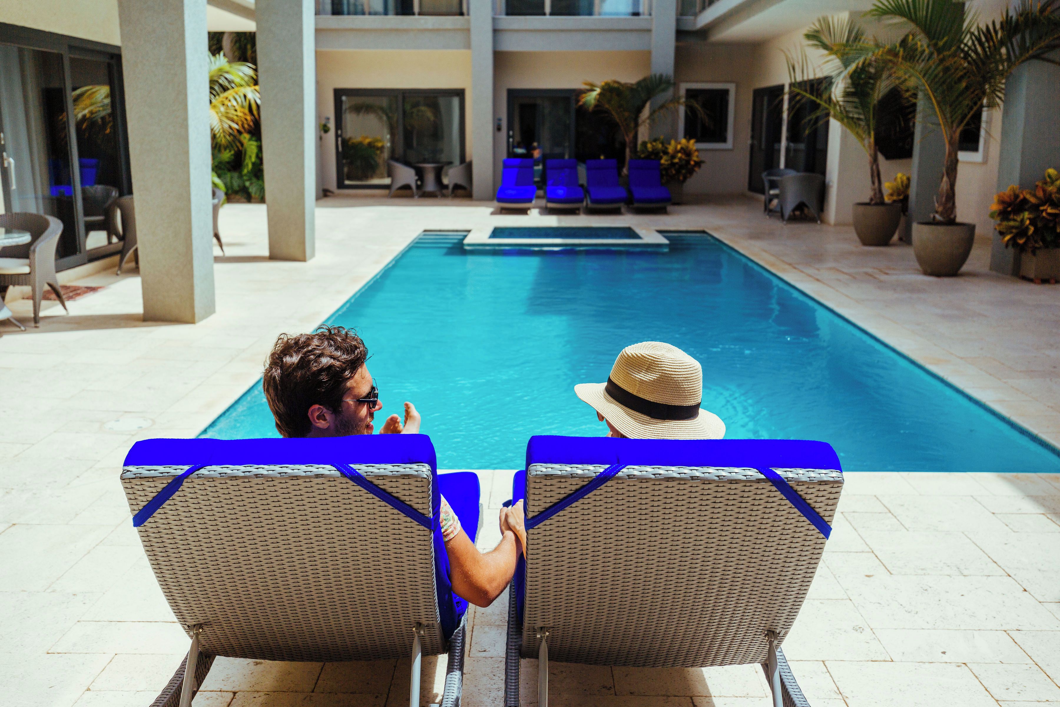 Une piscine avec des chaises longues et des plantes en pot.