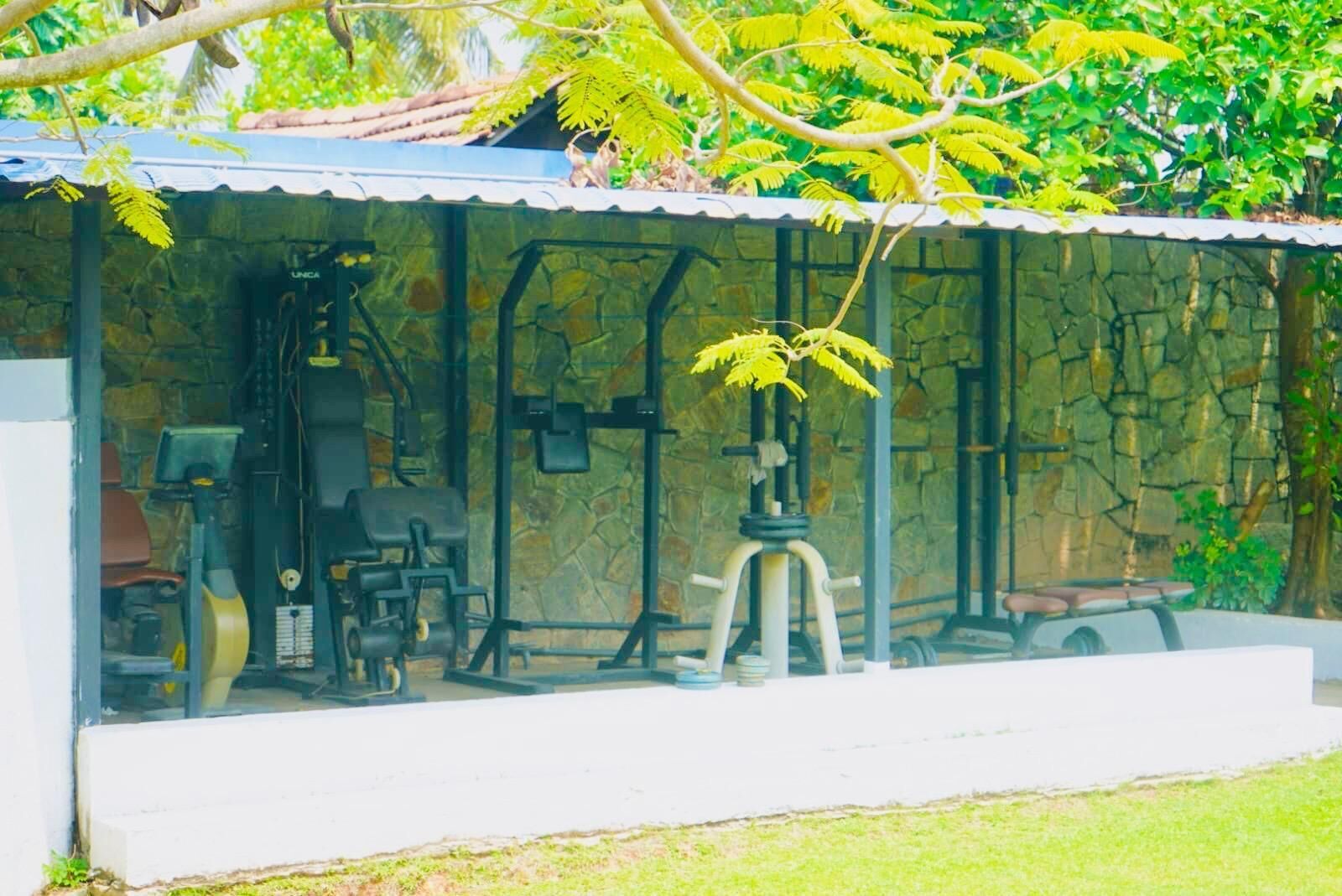 A covered outdoor area with a stone wall, a mechanical device, and a bench.