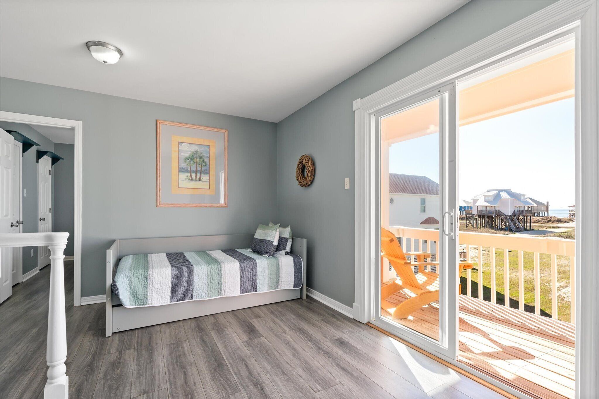 Une chambre à coucher avec un lit, un tableau encadré et une vue sur la plage, visible à travers une porte coulissante.