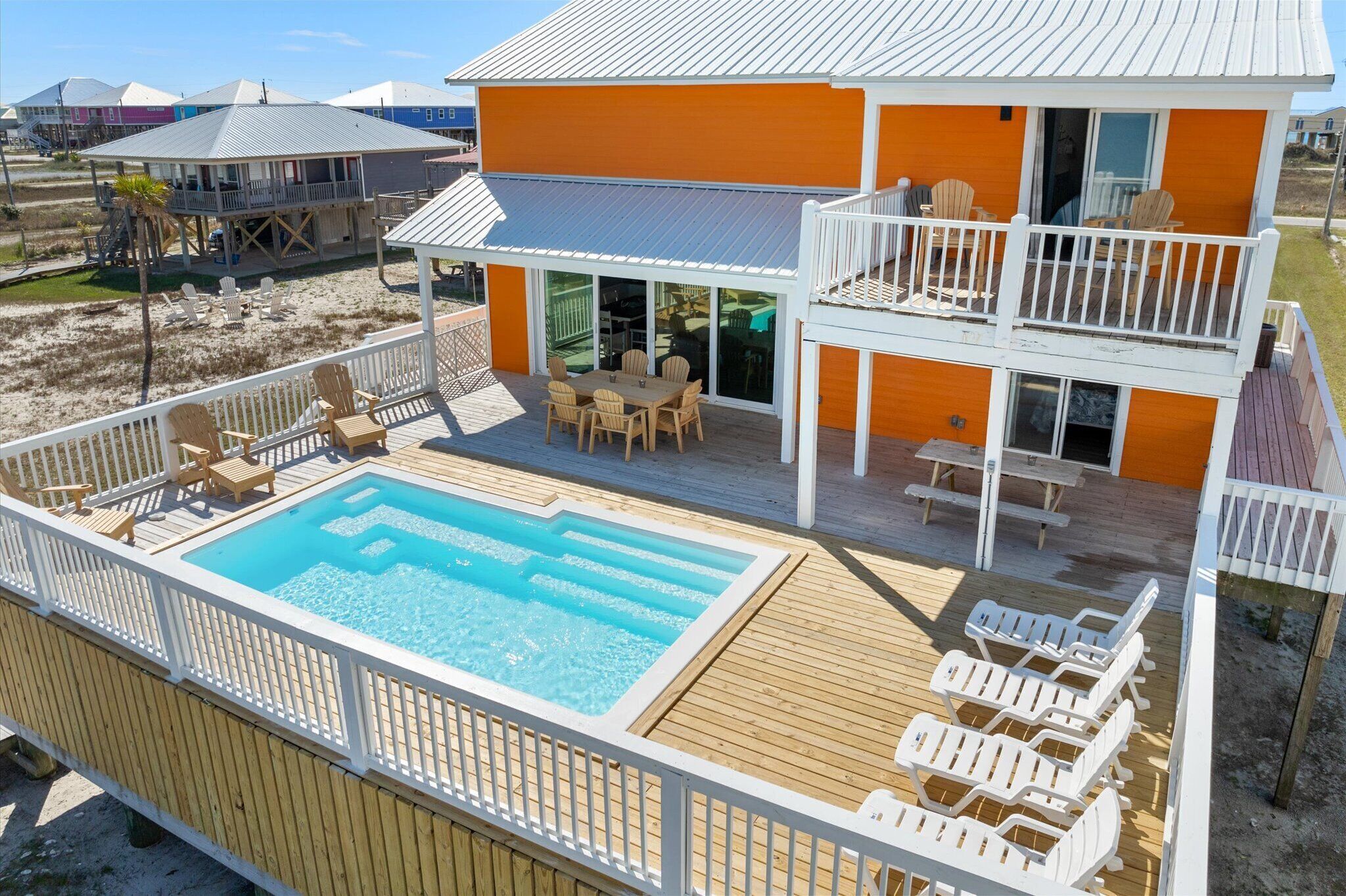 A two-story house with a swimming pool, deck chairs, and a covered patio.