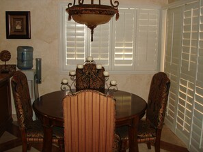 A dining room with a round table, ornate chairs, a chandelier, and a window with blinds. - Spacious, Comfortable 2 Master Bedroom Condo - outstanding location!! (Las Vegas)