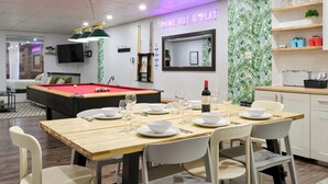 A modern room with a pool table, dining table set for four, a television, and a neon sign. - MTLVR #09 | Central Plateau, A/C, Ping-Pong (Montreal)