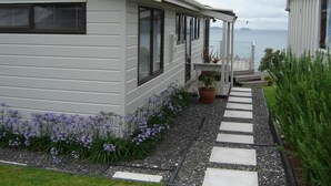 A modern house with a stone pathway leading to a porch with potted plants. - Paku Paradise, Tairua. (Tairua)