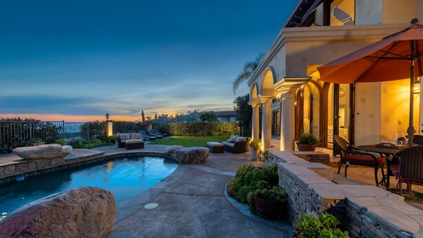 A pool area with stone tiles, large rocks, and outdoor furniture.