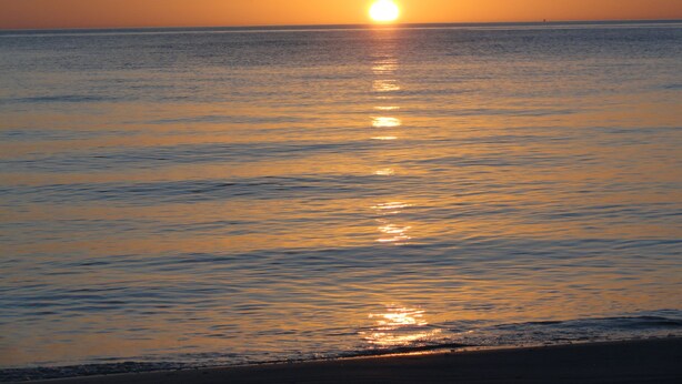 Un atardecer sobre un mar tranquilo con horizonte visible.