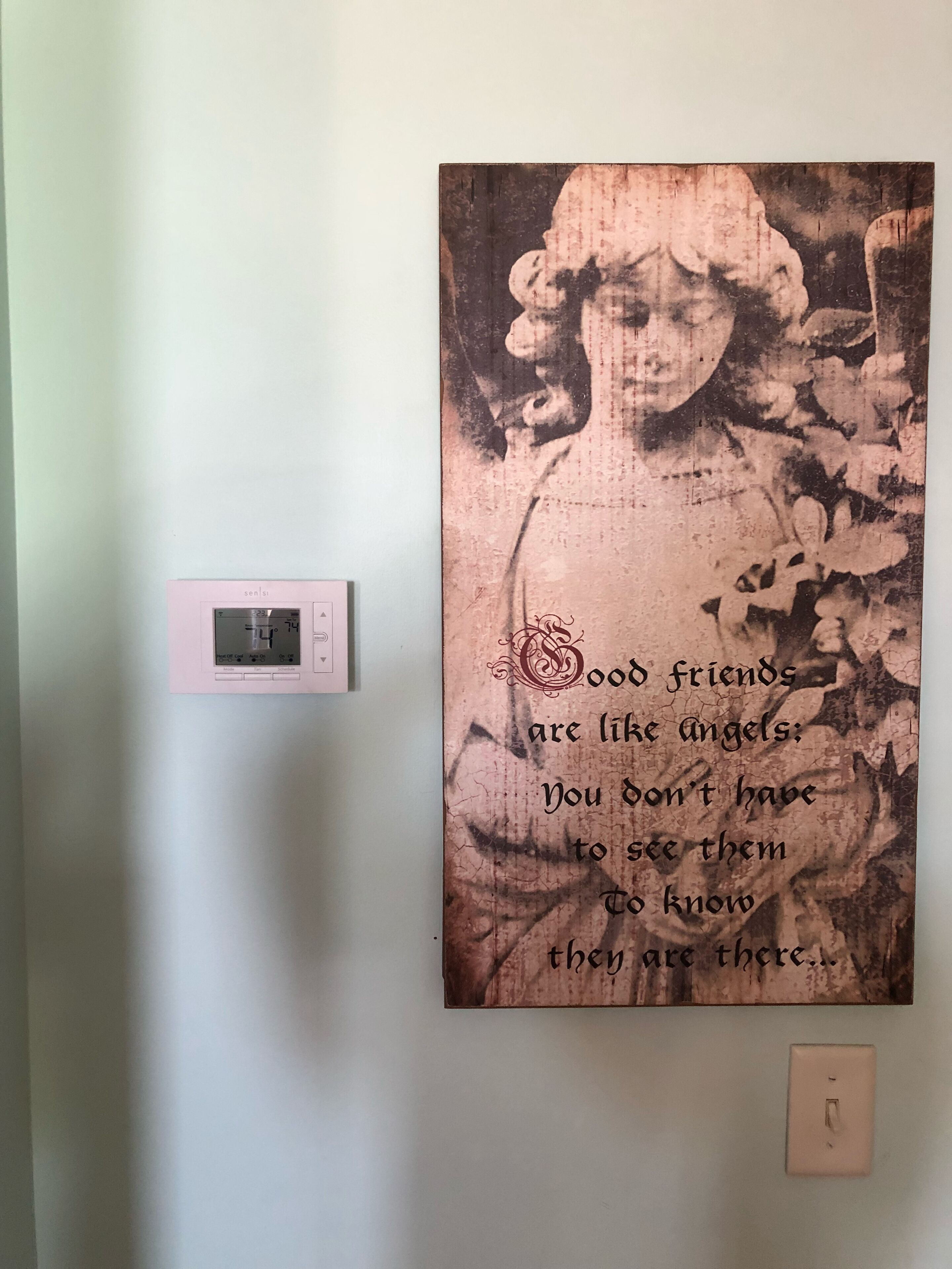 A wall with a poster featuring a quote and a thermostat.