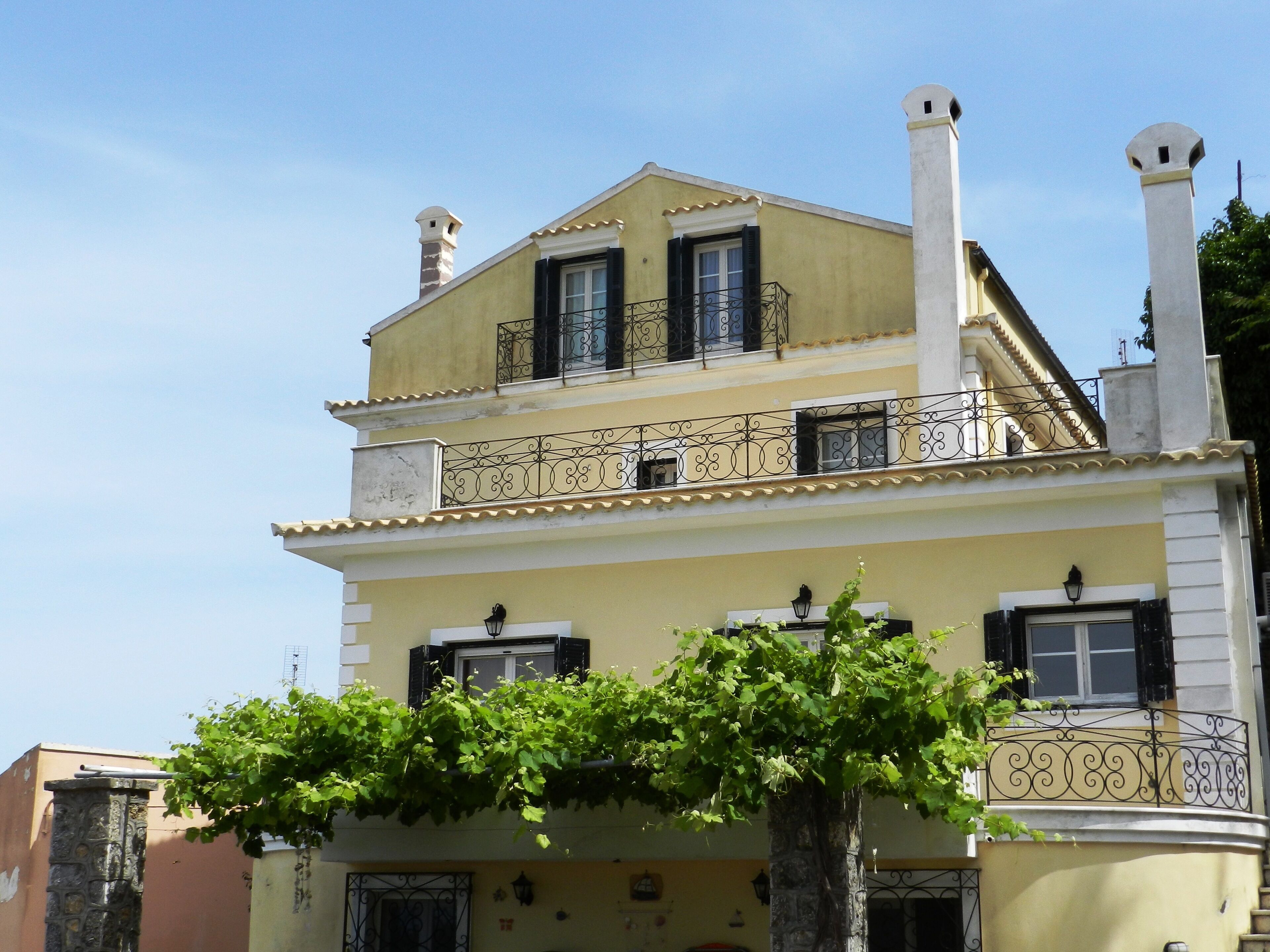 A two-story building with a balcony, a chimney, and a tree in front.
