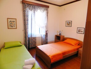 Un dormitorio con una cama individual, un sofá verde y una mesita de noche con lámpara.
