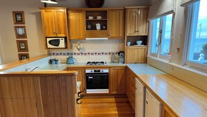 A kitchen with wooden cabinets, a stove, oven, and a window with a view. - The Lodge of Stanley (Stanley)