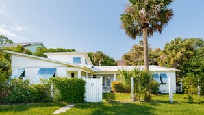 A two-story house with a covered porch, a small garden, and a palm tree. - Private Home Located Two Blocks from Restaurants/Shops & 1 Street From Beach! (Folly Beach)
