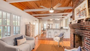 A spacious living room with a wooden ceiling, a fireplace, and a kitchen in the background. - Private Home Located Two Blocks from Restaurants/Shops & 1 Street From Beach! (Folly Beach)