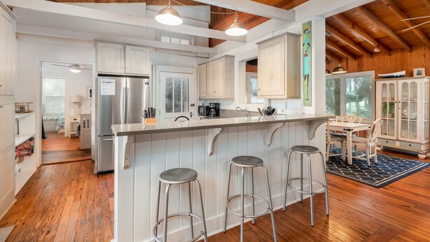 A spacious kitchen with a central island, bar stools, and wooden flooring. - Private Home Located Two Blocks from Restaurants/Shops & 1 Street From Beach! (Folly Beach)