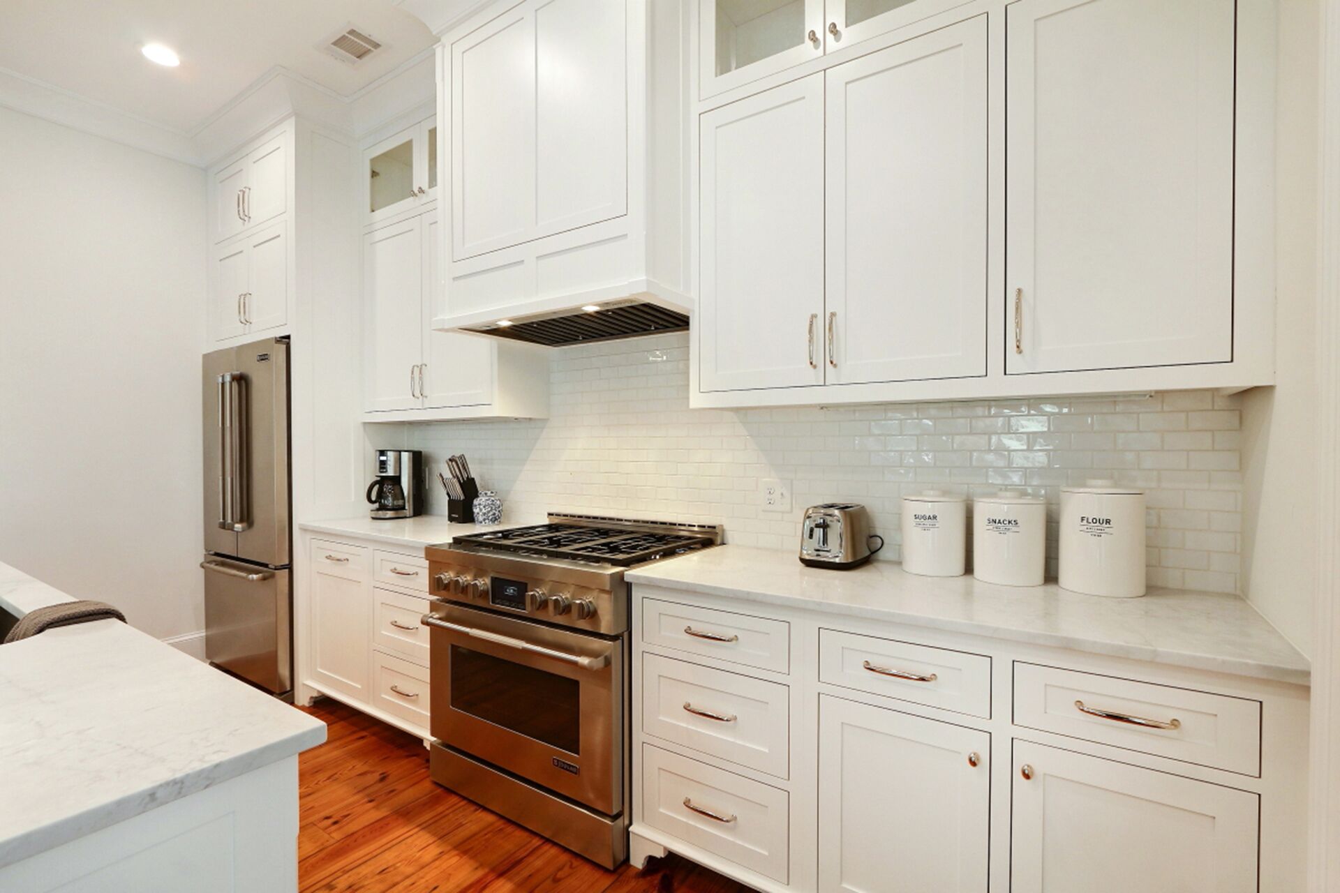 A modern kitchen with white cabinetry, stainless steel appliances, and a tiled backsplash.