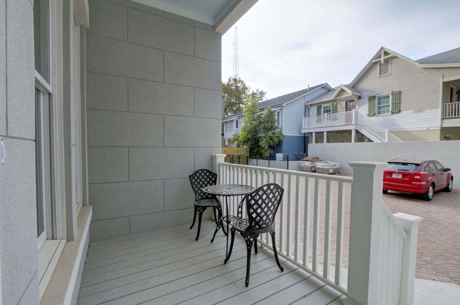 A covered porch with two metal chairs and a small round table.