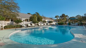 A swimming pool with lounge chairs and a white fence.