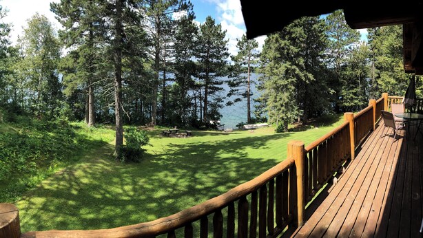 Una terraza de madera con vistas a un lago y un bosque.