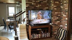 Ein Wohnzimmer mit Backsteinwand, Fernseher, Kamin und Essbereich.