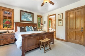 A spacious bedroom with a large bed, wooden headboard, and a ceiling fan.